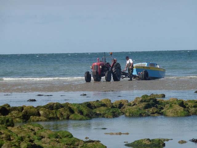 A boat hauled across the beach by tractor